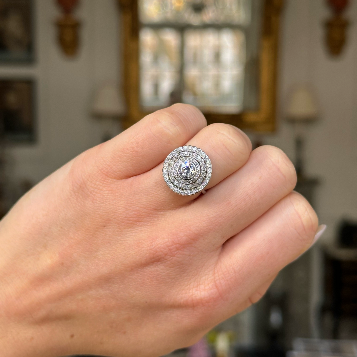 Art Deco diamond target cluster ring worn on closed hand.