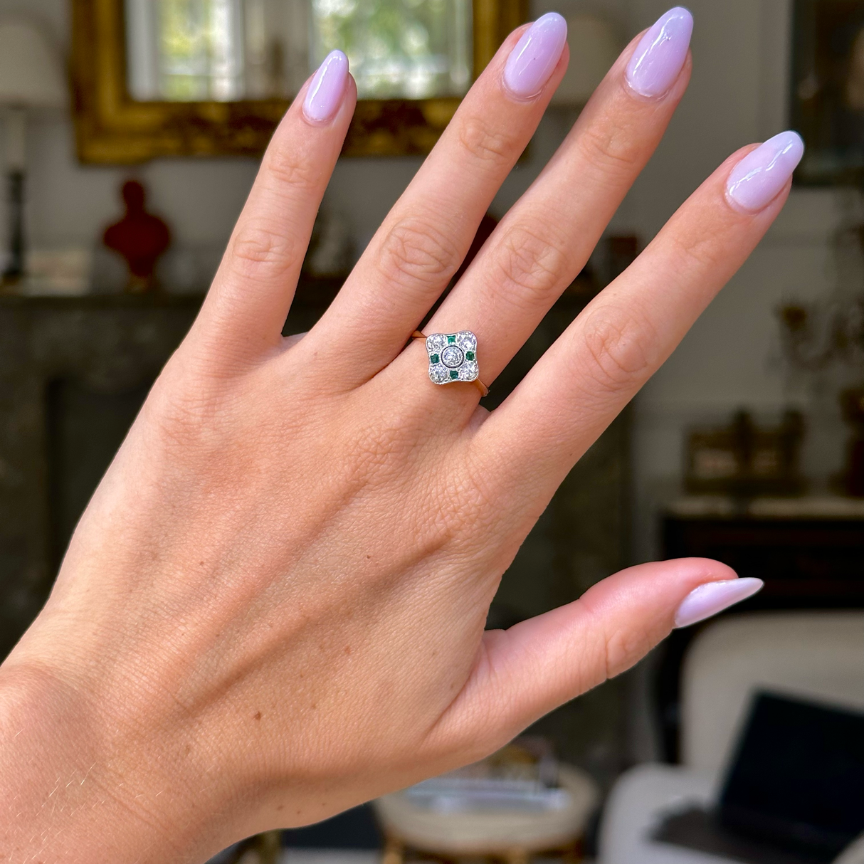 Art Deco emerald and diamond kite shaped ring, worn on hand, front view.