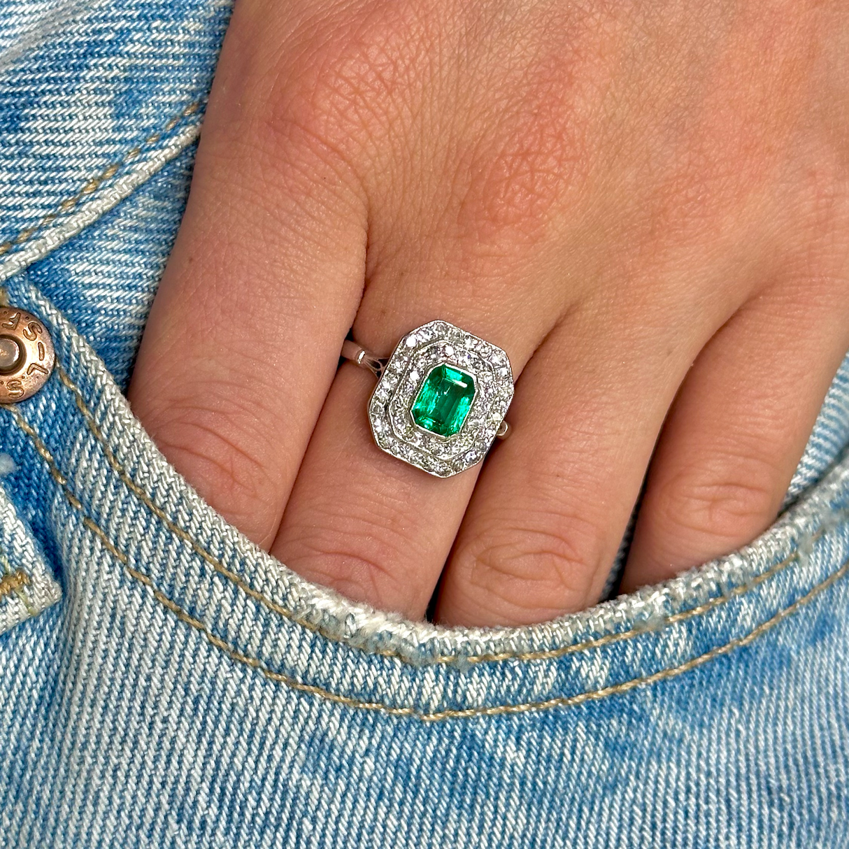 Vintage emerald and diamond cluster ring, worn on hand.