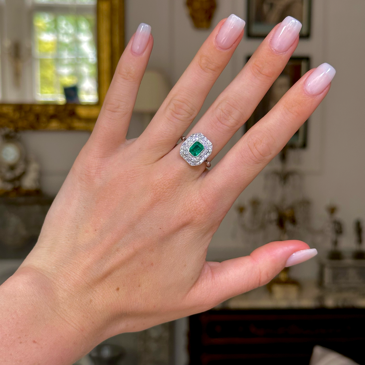 Vintage emerald and diamond cluster ring, worn on hand.