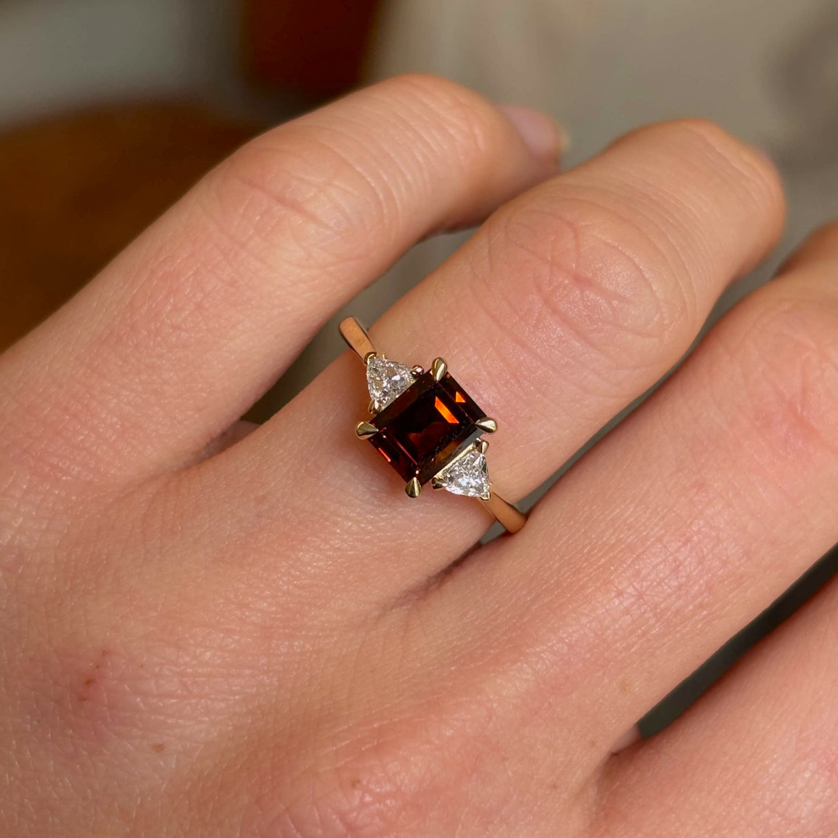 Brown diamond three-stone engagement ring on hand close up
