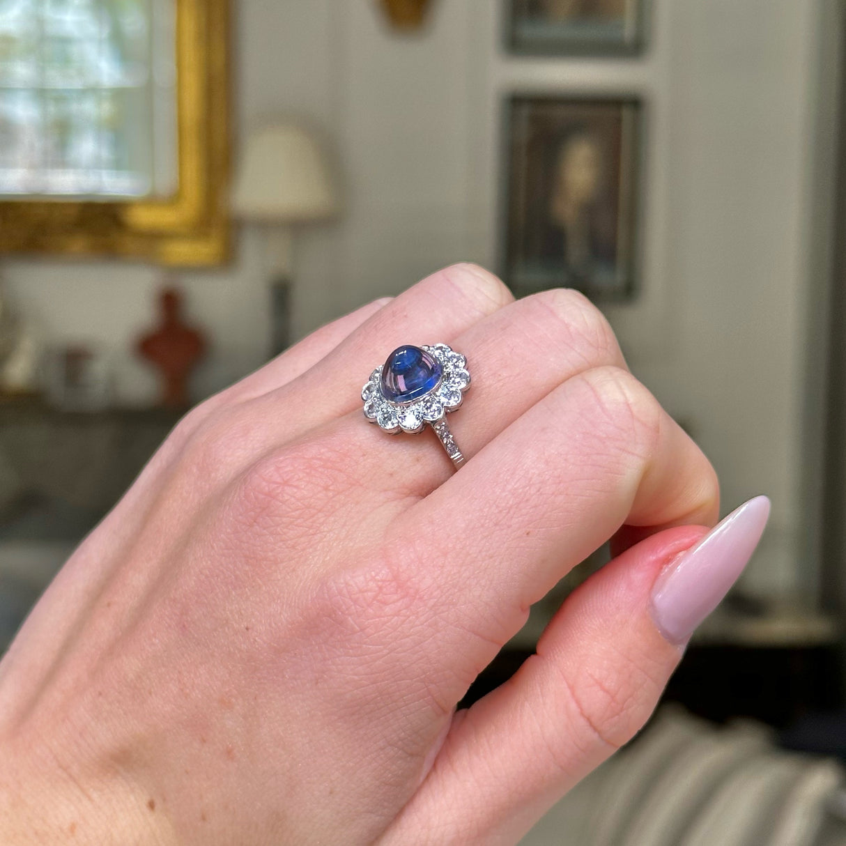 cabochon sapphire and diamond cluster ring on closed hand