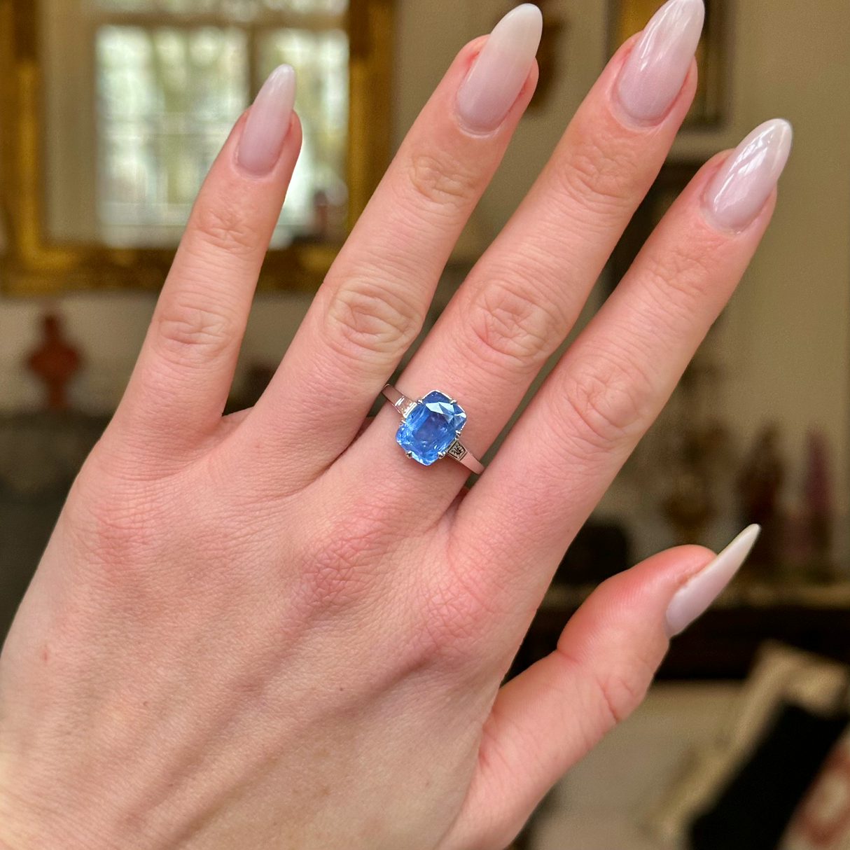 Solitaire sapphire engagement ring worn on hand.