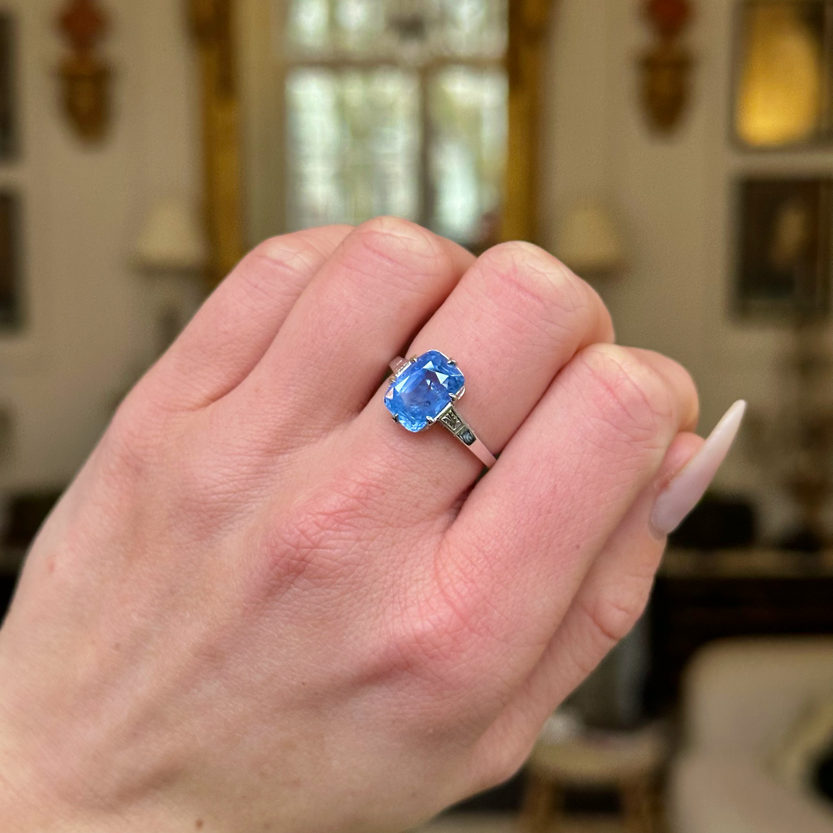 Solitaire sapphire engagement ring worn on closed hand.