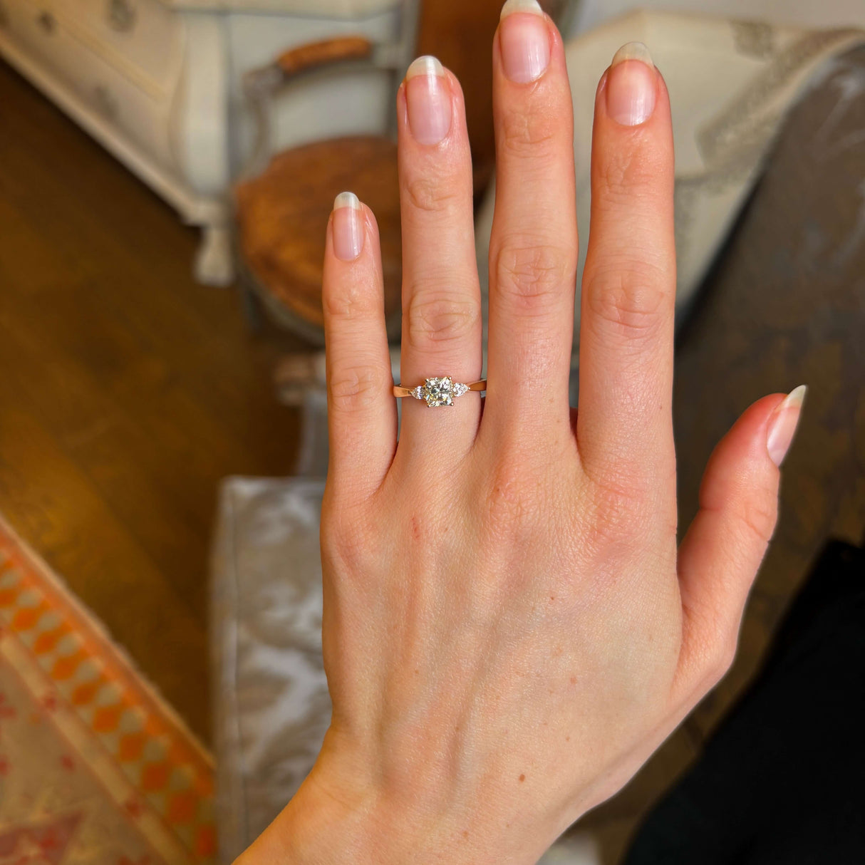 Diamond three-stone engagement ring worn on hand to show scale