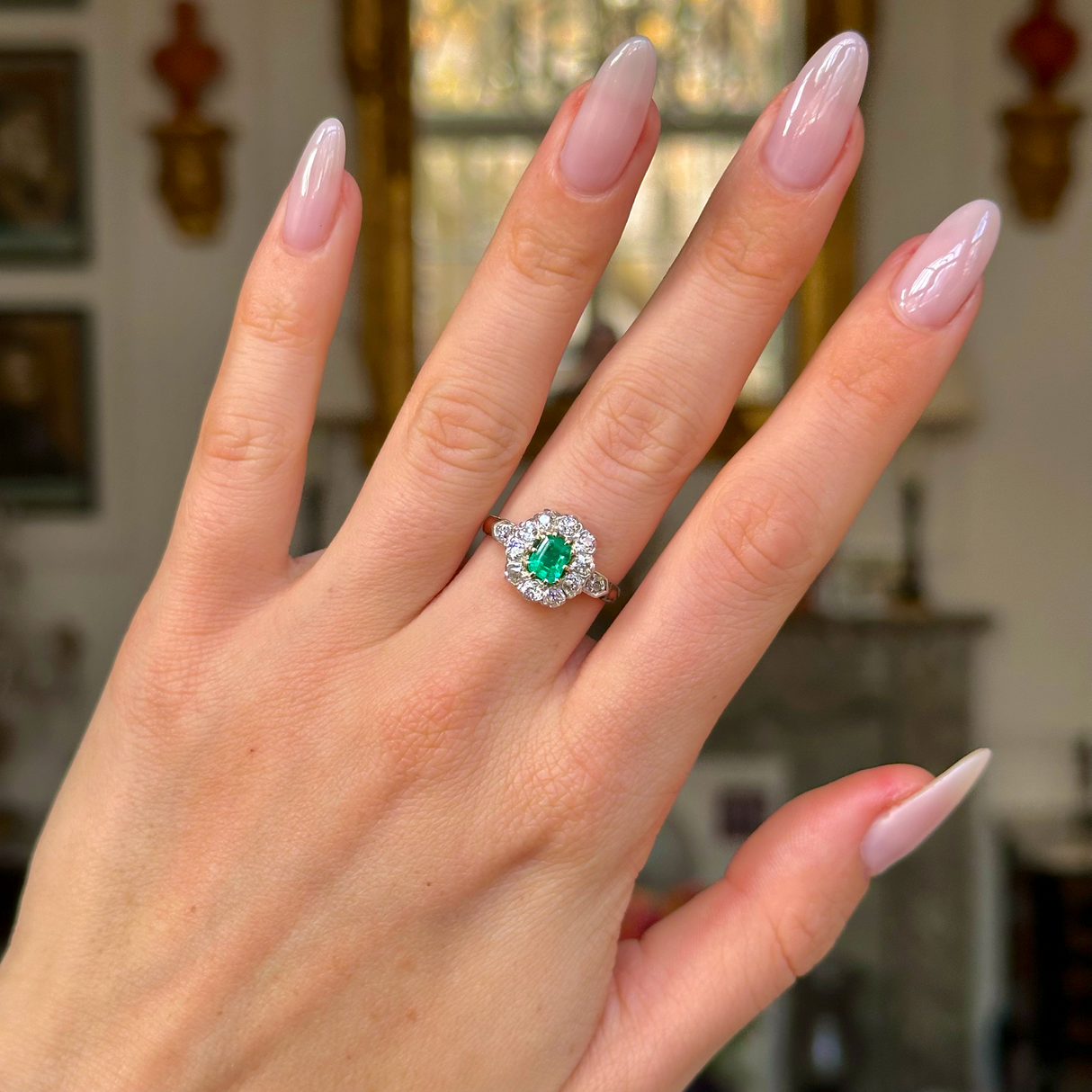 Edwardian emerald and diamond ring worn on hand.