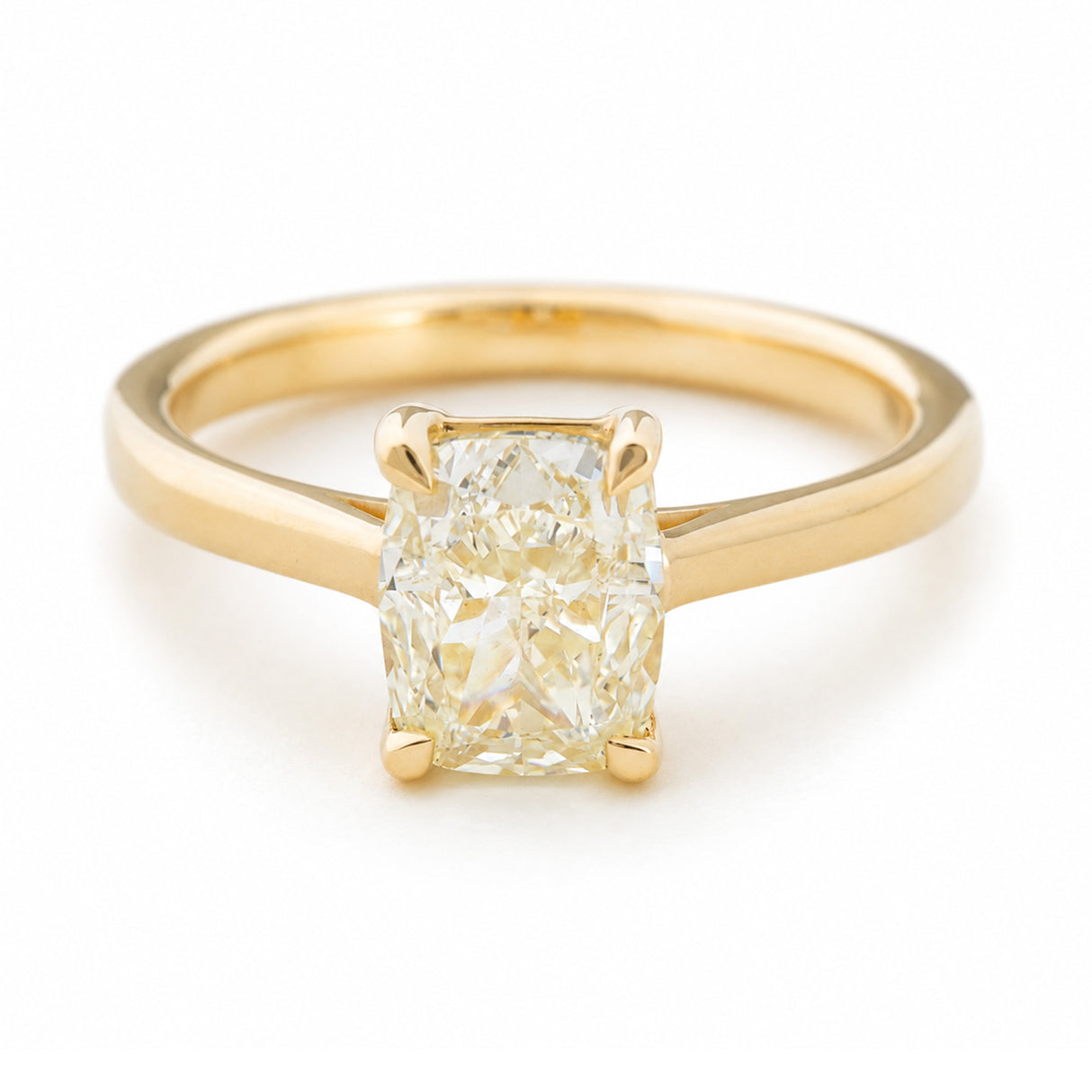 Antique-inspired, cushion-cut diamond solitaire engagement ring in yellow gold seen from a slight angle to show the band against a white background