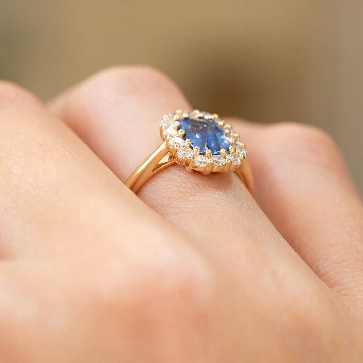 Side view of a vintage-inspired sapphire and diamond cluster ring worn on the hand, showing the elevated 14ct yellow gold setting.