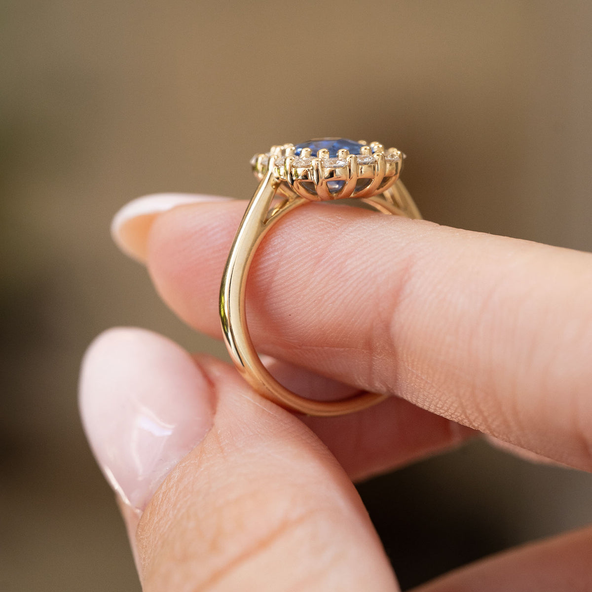 Profile view of an antique-inspired sapphire cluster ring, revealing the raised diamond halo setting and polished yellow gold band.