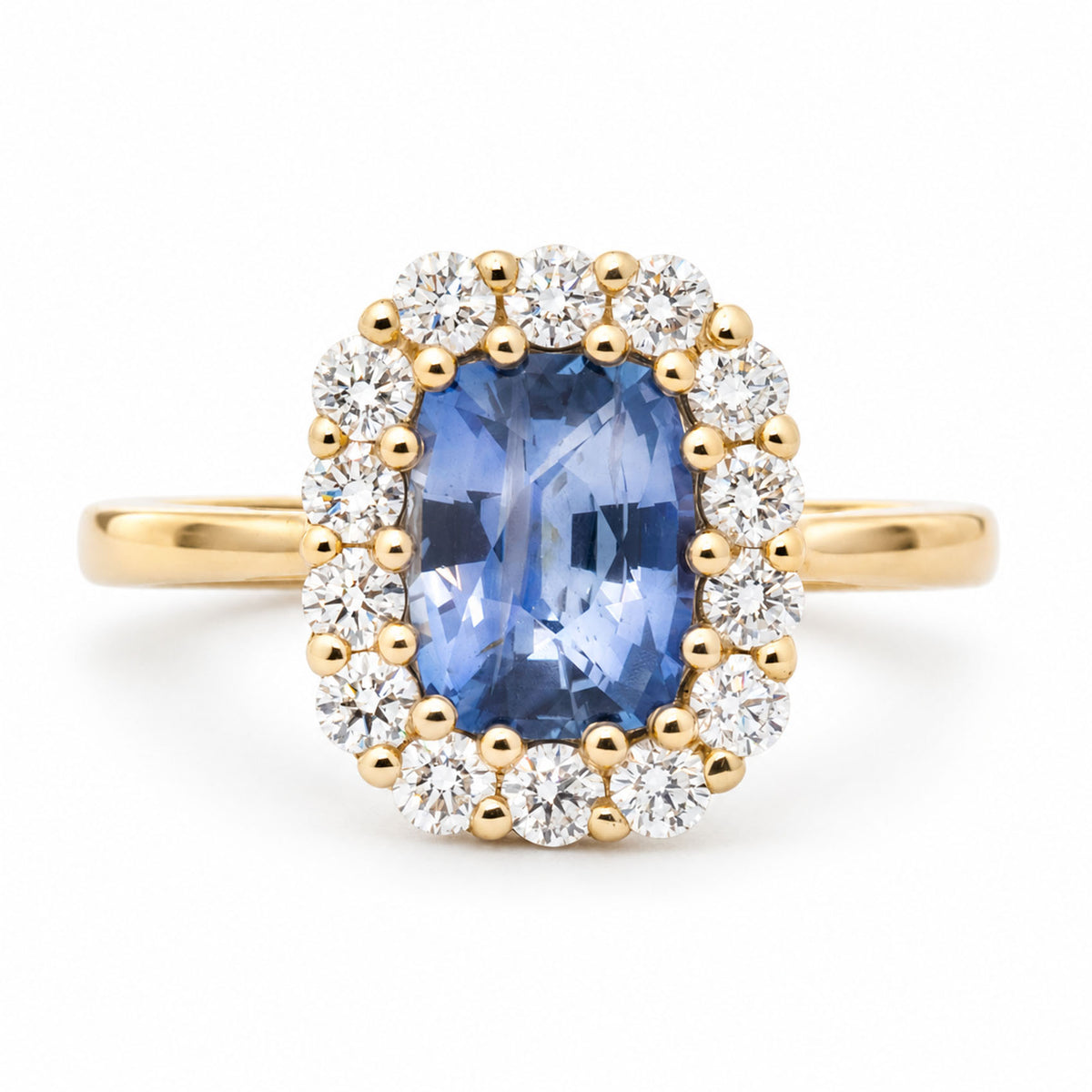 Front view of an antique-inspired cushion-cut blue sapphire engagement ring in 14ct yellow gold, surrounded by a halo of round brilliant-cut diamonds.