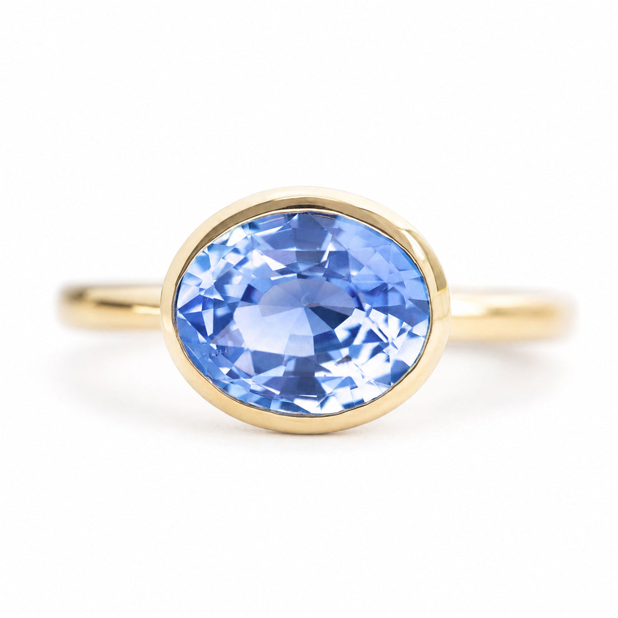 An close-up of an antique-inspired, blue oval sapphire solitaire ring set in yellow gold.