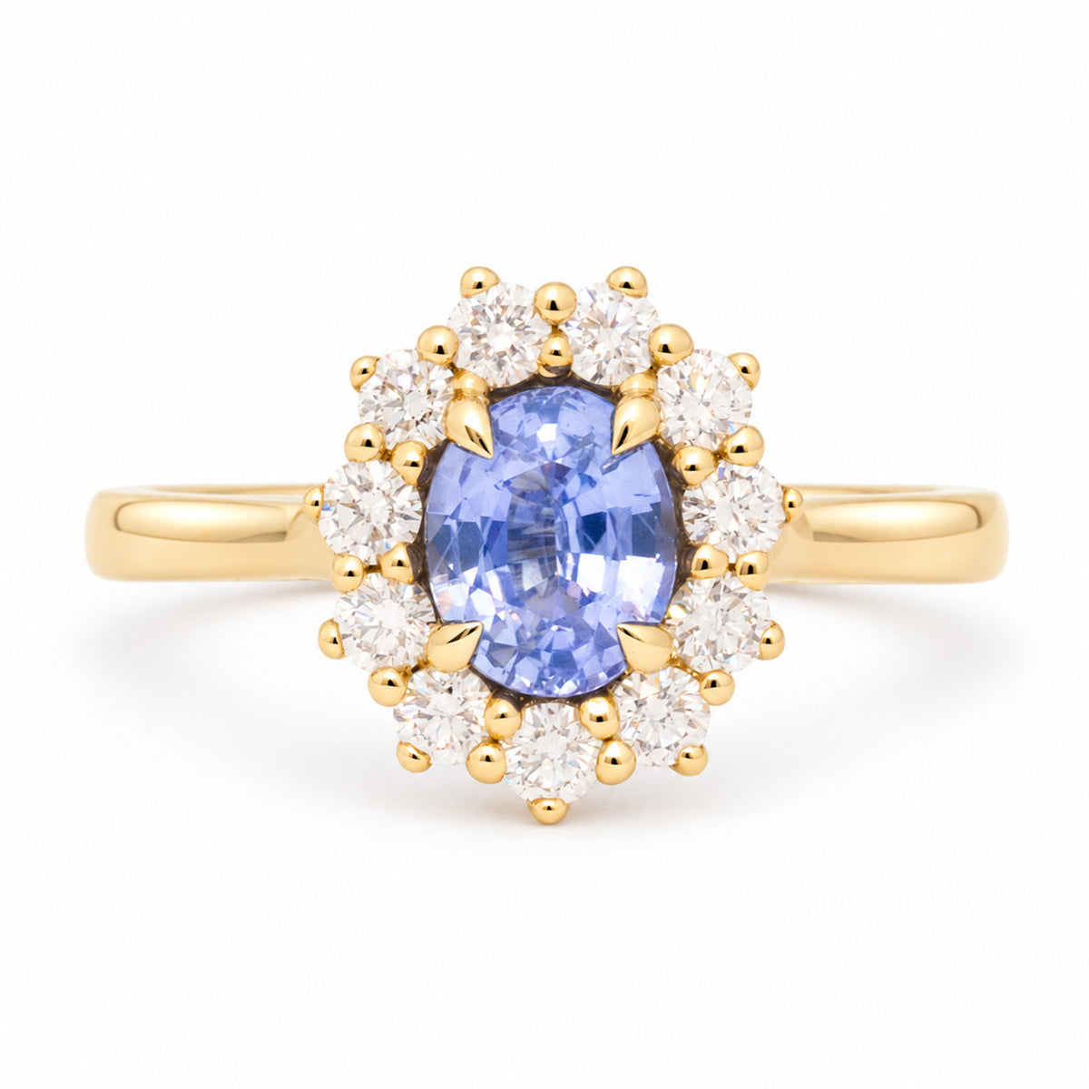 Antique-inspired oval-cut blue sapphire and diamond cluster engagement ring in yellow gold, framed by a halo of round diamonds.