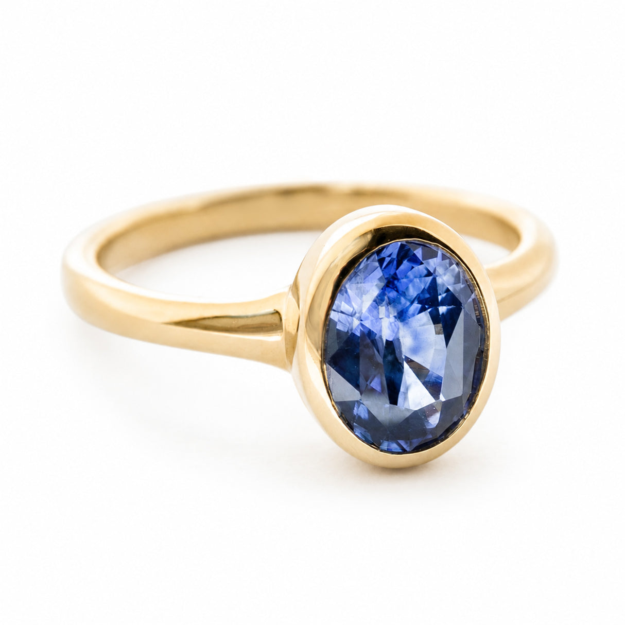 A side view of a vintage-inspired 14ct yellow gold ring set with an oval deep blue sapphire.