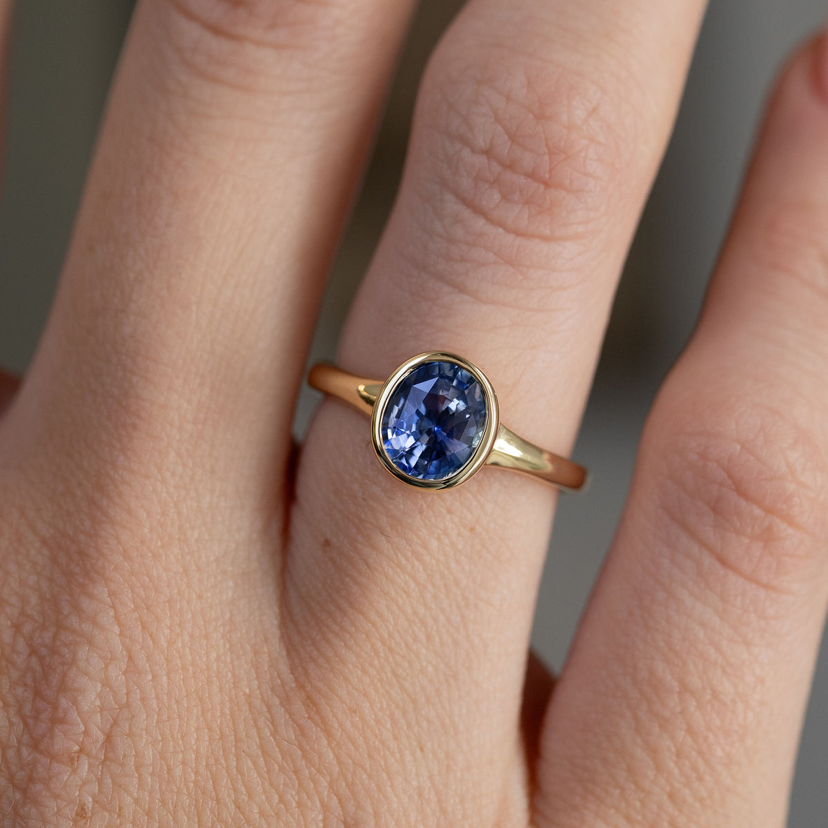 Detailed close-up of the sapphire solitaire on the hand, emphasising its deep blue tones and smooth gold surround.