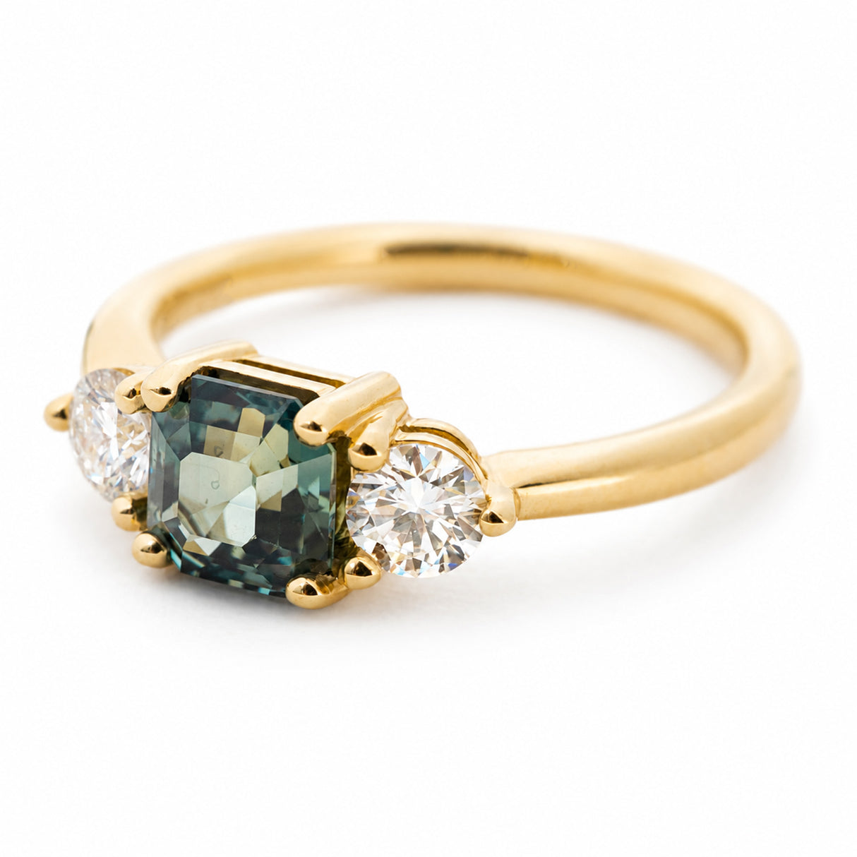 A side profile of a vintage-inspired teal-green sapphire and diamond three-stone engagement ring in 14ct yellow gold.
