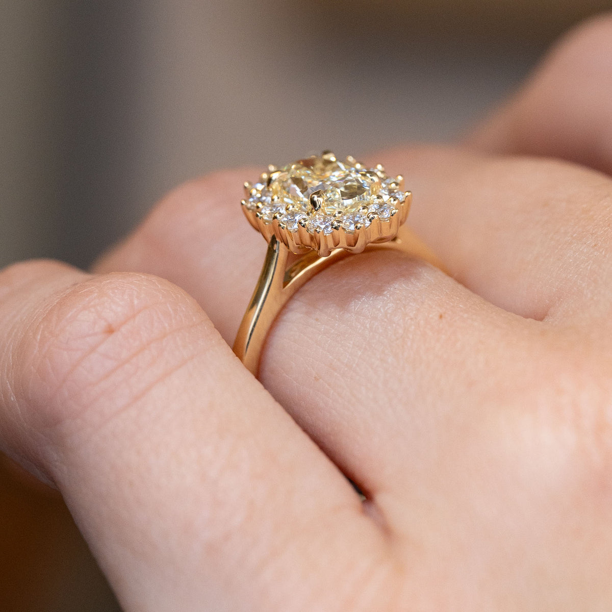 Side-angle view of the yellow diamond cluster ring worn on a hand, highlighting the elevated setting and yellow gold detailing.