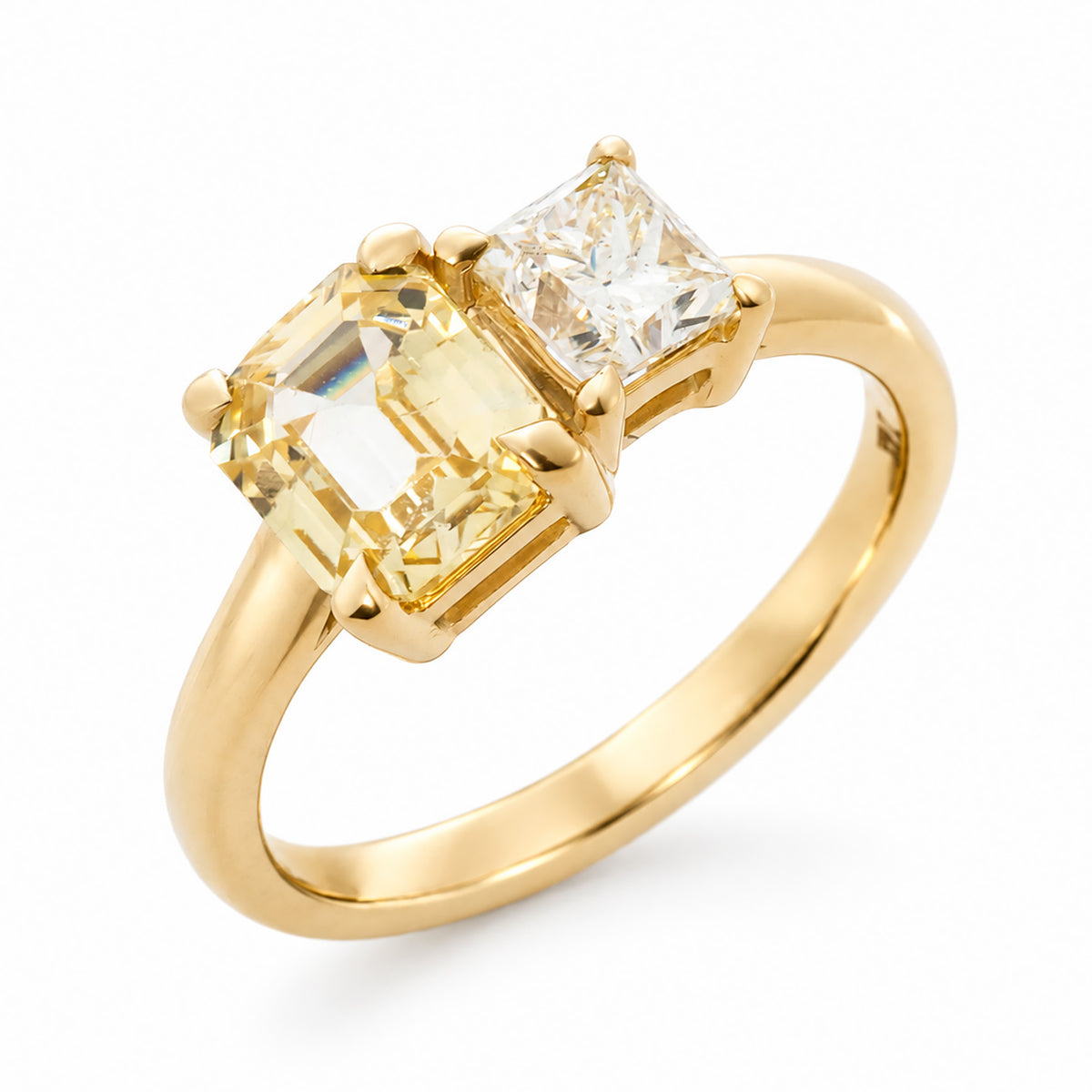 A three-quarter profile of a vintage-inspired yellow gold toi et moi engagement ring set with a diamond and yellow sapphire.
