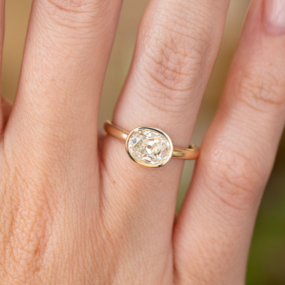 Close-up of an elongated cushion-cut diamond solitaire ring in 14ct yellow gold, with a smooth rub-over setting and vintage-inspired character.