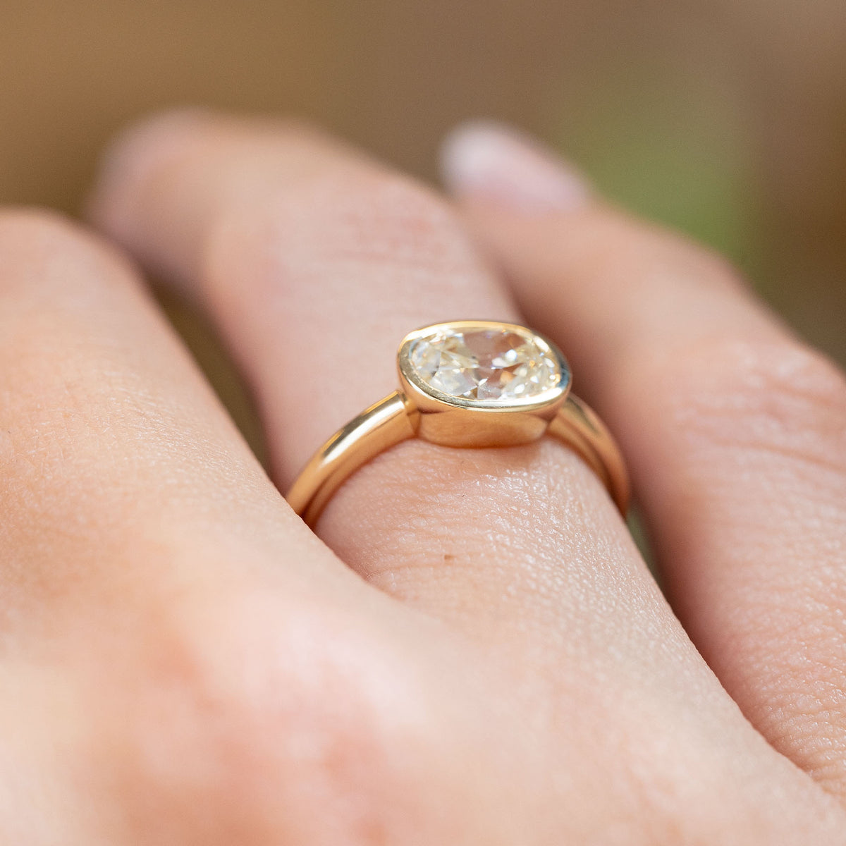 Side view of a vintage-inspired old-mine cut diamond ring worn on the hand, revealing the raised setting and slender yellow gold band.