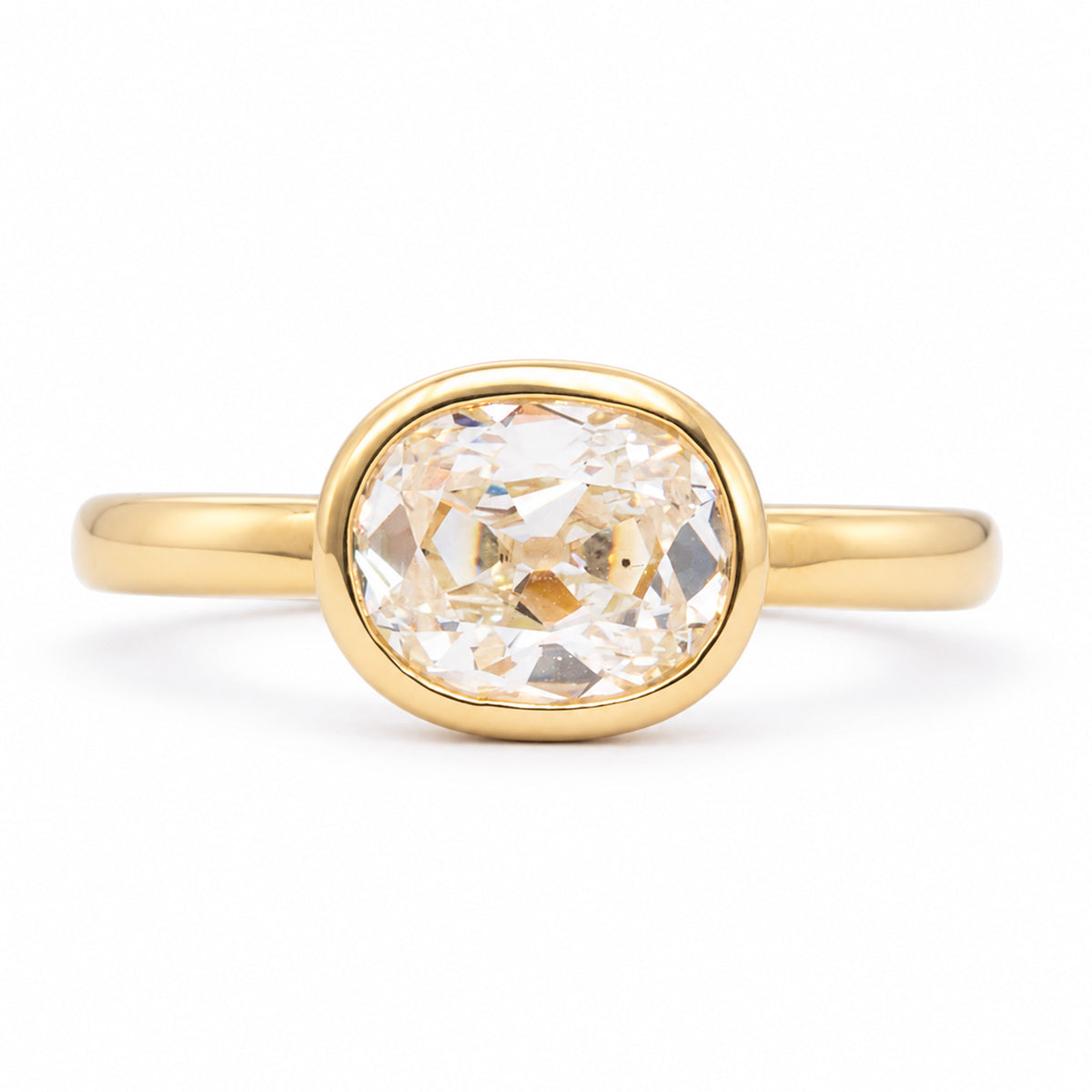 Front view of an antique-inspired elongated cushion old-mine cut diamond solitaire engagement ring in a polished 14ct yellow gold rub-over setting.