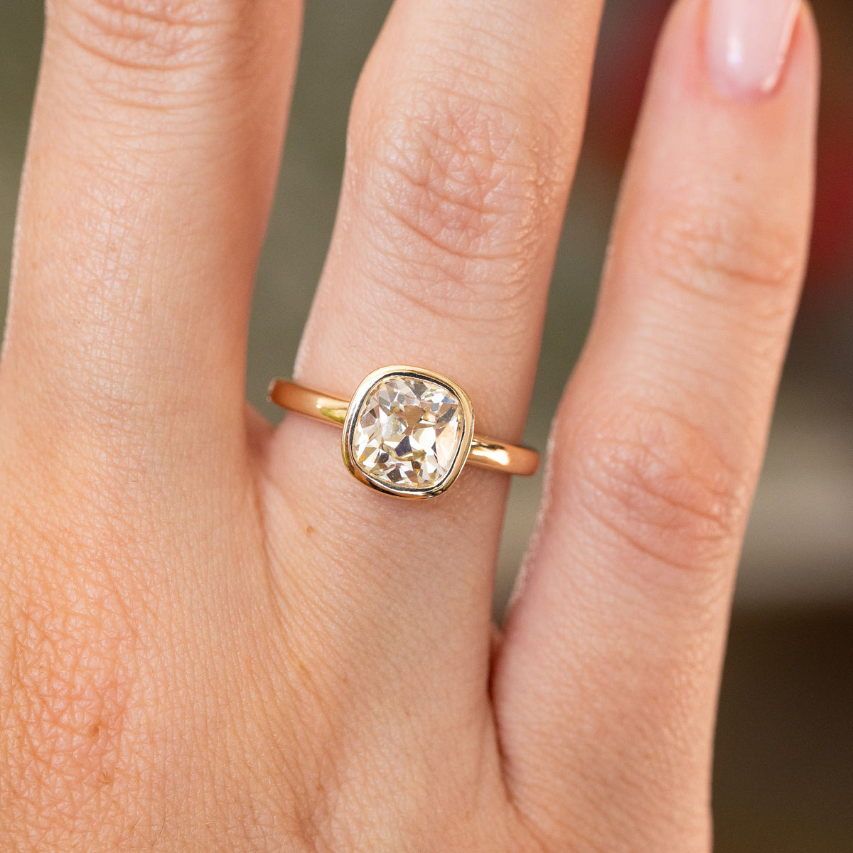 Close-up of an antique-inspired cushion diamond solitaire in yellow gold, featuring a warm yellow tint and softly rounded setting.