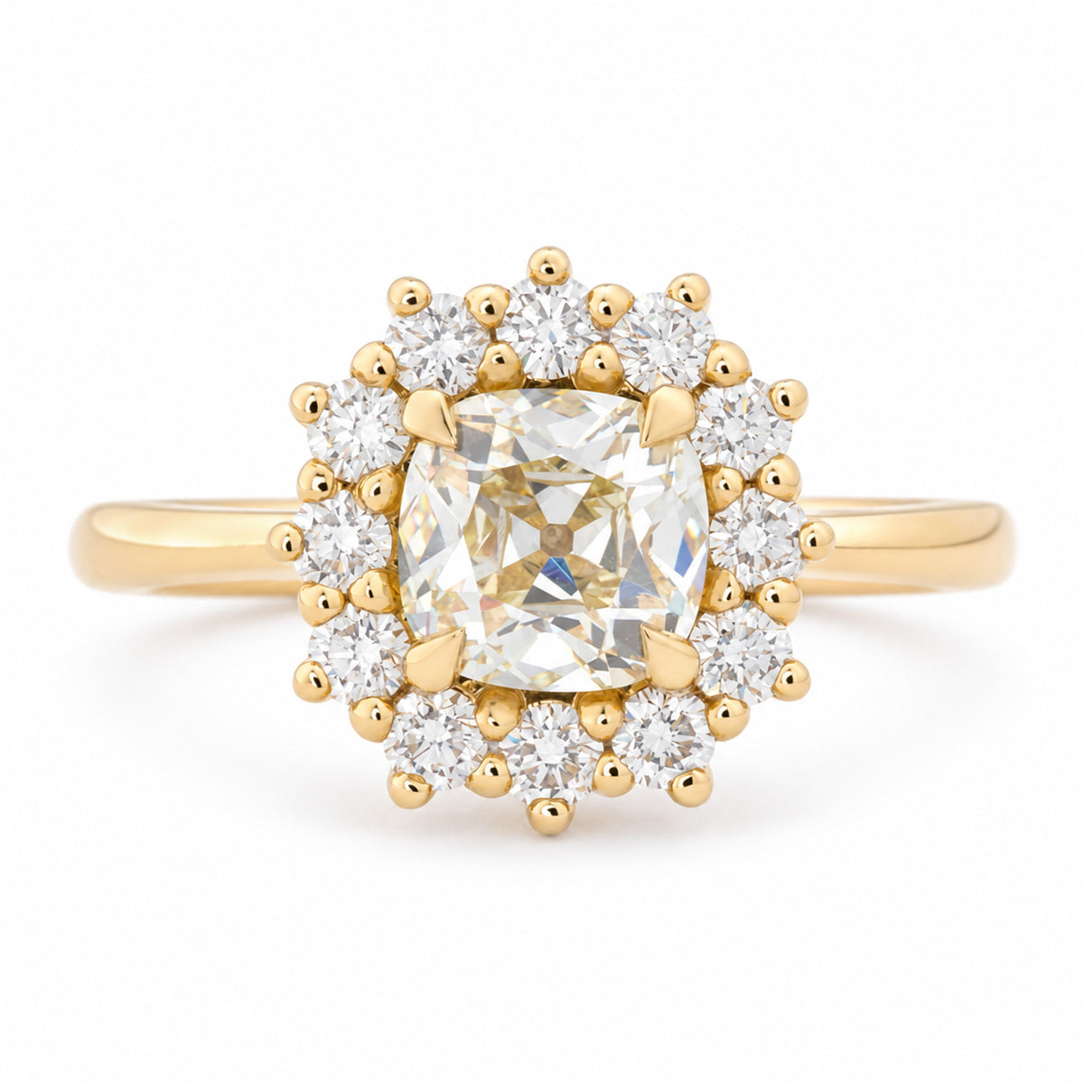 Antique-inspired yellow cushion old-mine cut diamond cluster engagement ring in yellow gold, surrounded by a halo of brilliant-cut white diamonds.