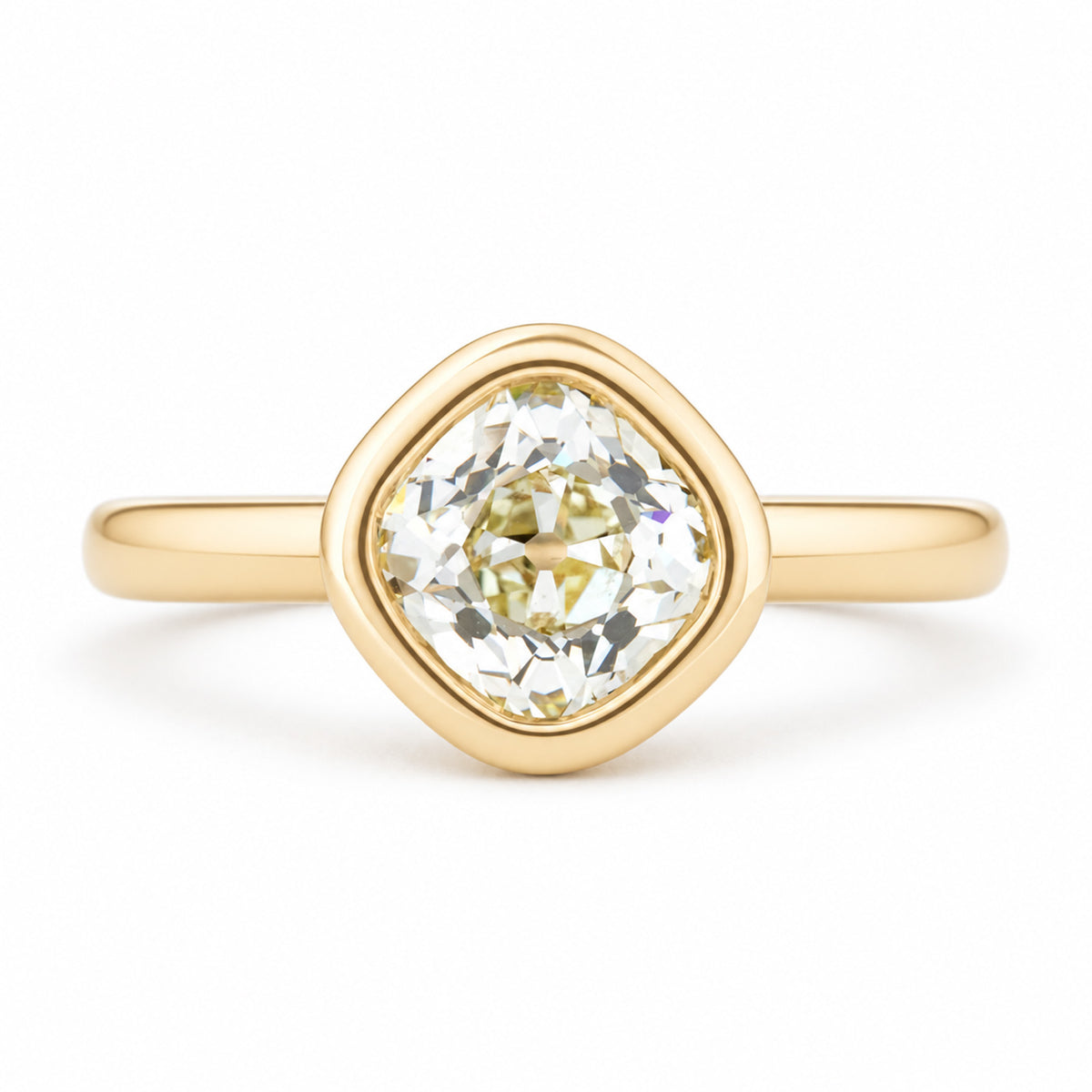 An antique-inspired solitaire engagement ring featuring an old mine-cut diamond in a rounded yellow gold bezel setting.