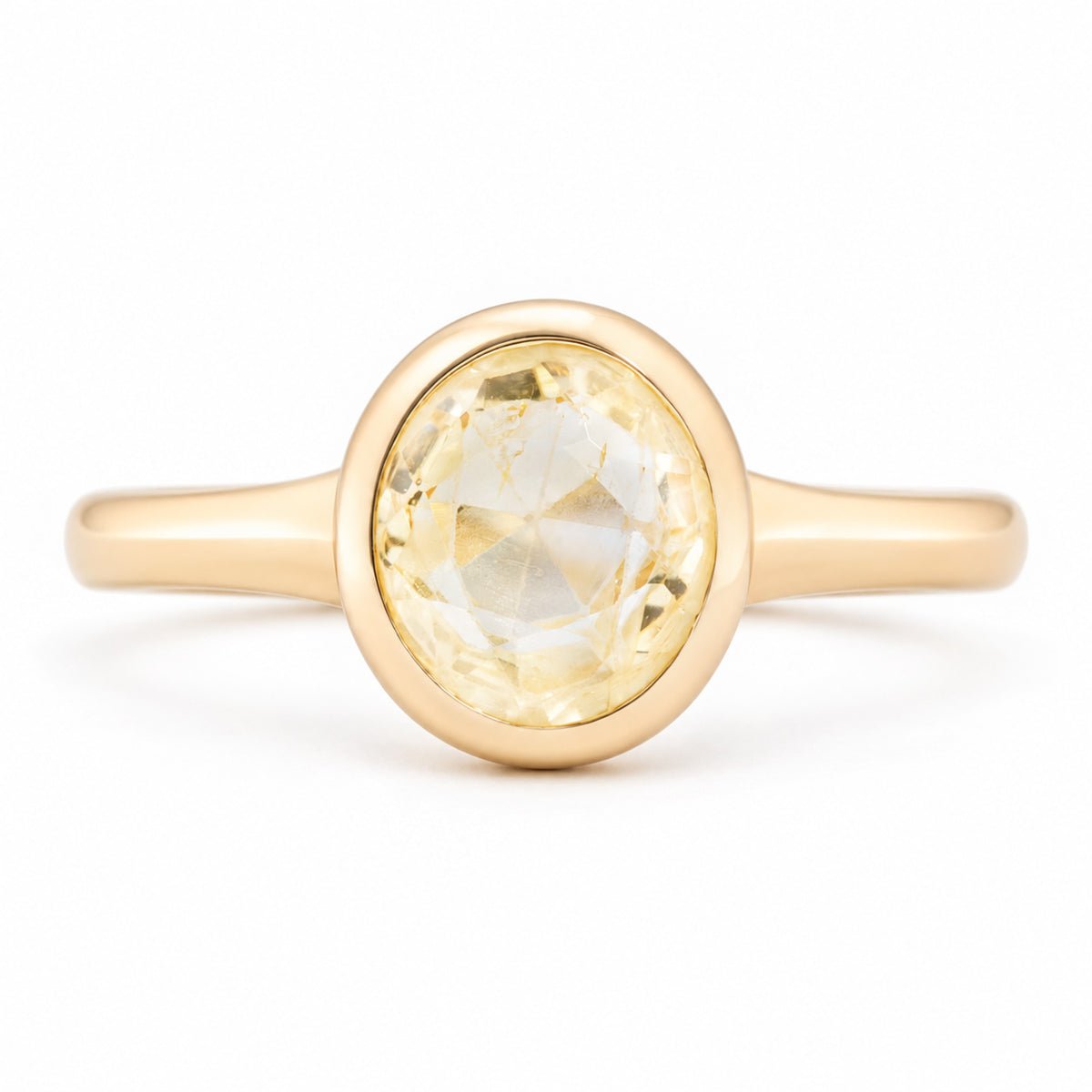 Front view of an antique-inspired pale yellow sapphire solitaire engagement ring in yellow gold, featuring an oval-cut sapphire in a smooth polished bezel setting.