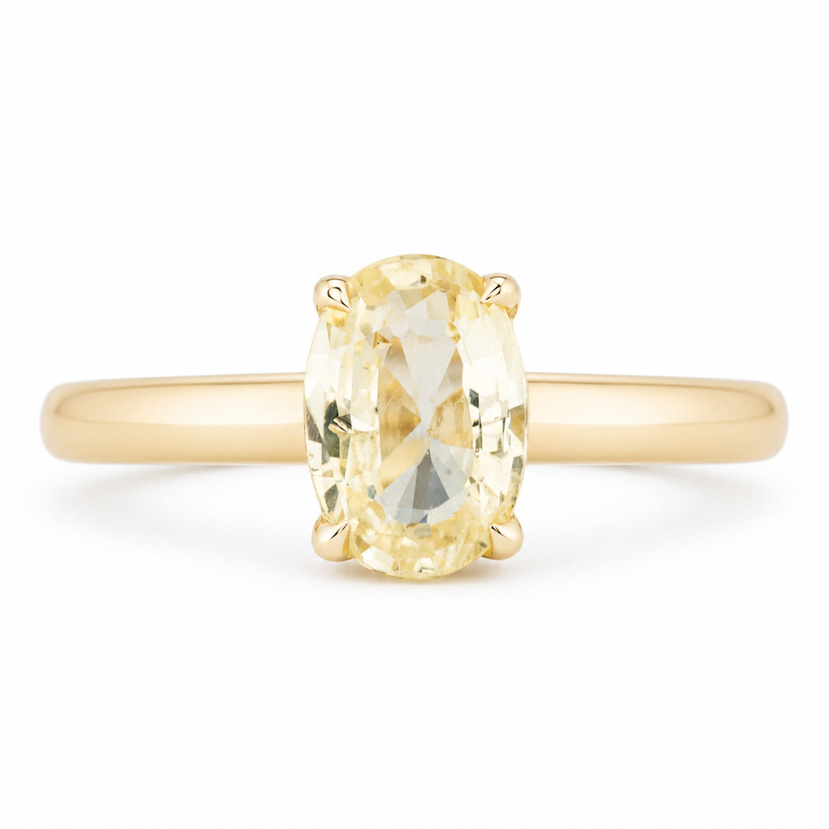 Front view of an antique-inspired engagement ring featuring an oval pale yellow sapphire held in a delicate four-claw yellow gold setting.