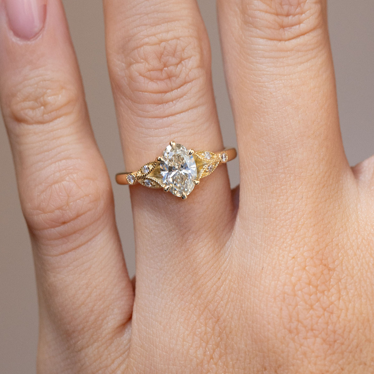 Engagement ring worn on the hand, showing its sparkling centre and ornate trefoil shoulders.