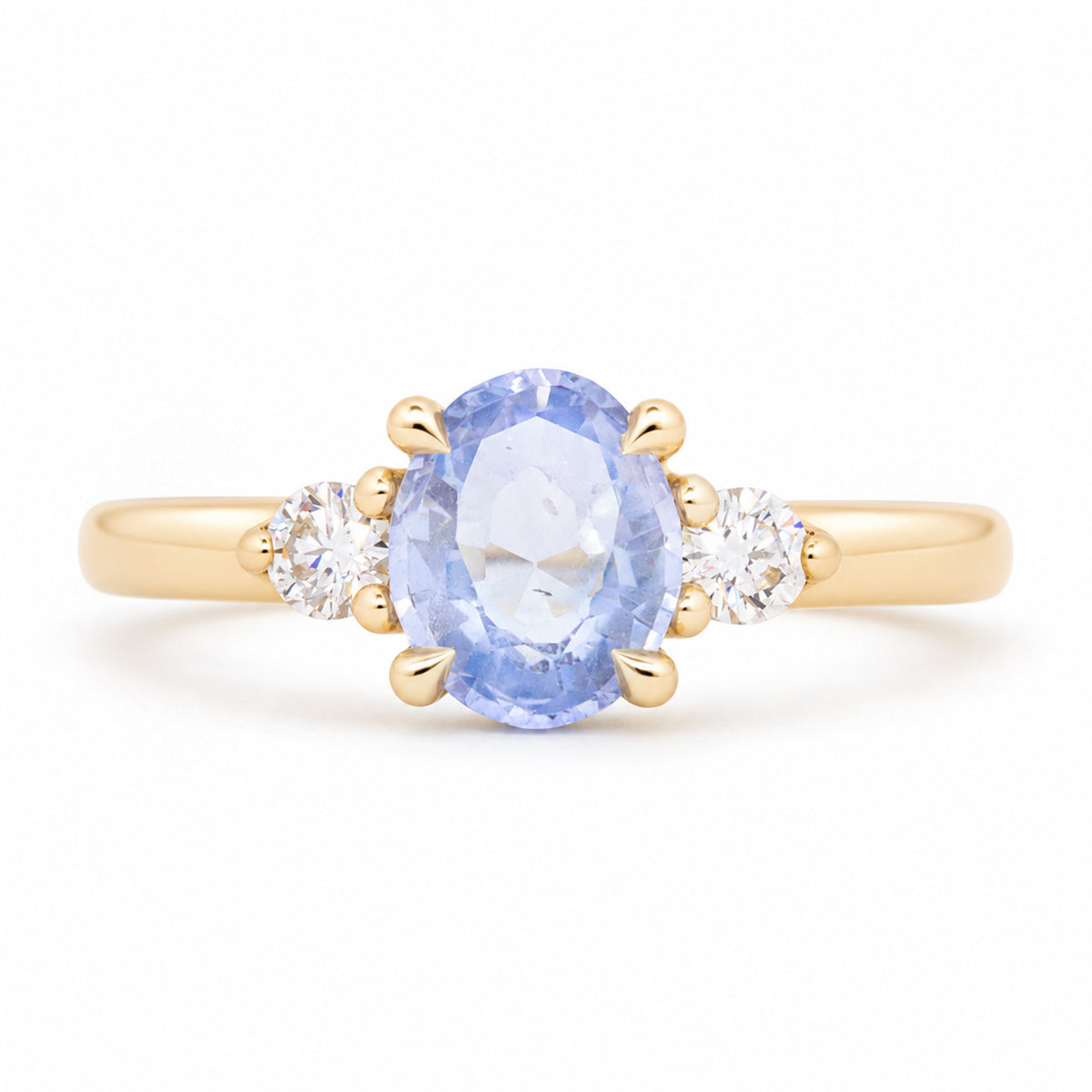 Antique-inspired blue oval sapphire and diamond three-stone engagement ring in yellow gold, featuring two round brilliant-cut diamond shoulders.