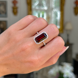 Red Garnet and diamond cluster ring worn on closed hand.