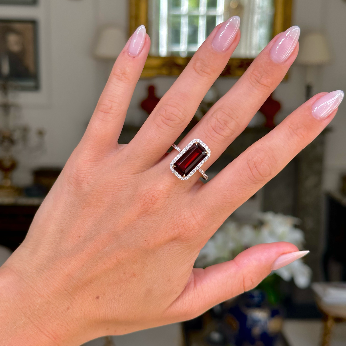 red garnet and diamond cluster ring, worn on hand, front view.