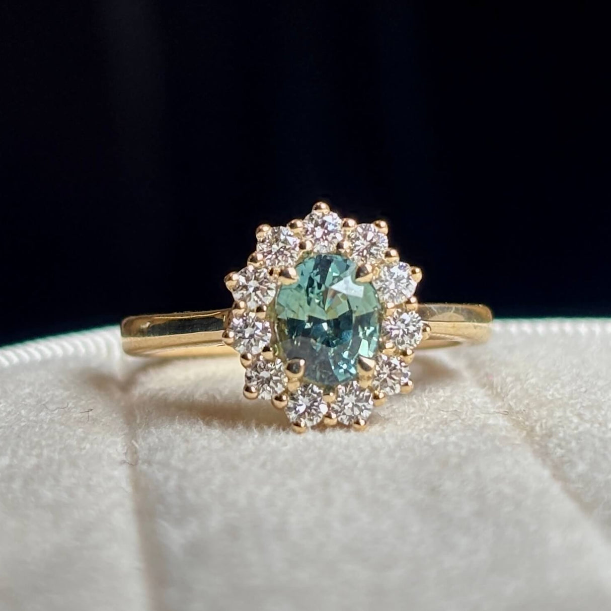 Green sapphire and diamond cluster engagement ring worn with wedding band to show scale.