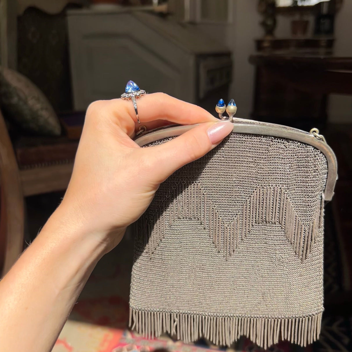 Profile of blue cabochon cut sapphire with an art deco chainmail bag with similar gemstones on clasp