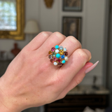 Multi gemstone cluster ring worn on closed hand, front view.