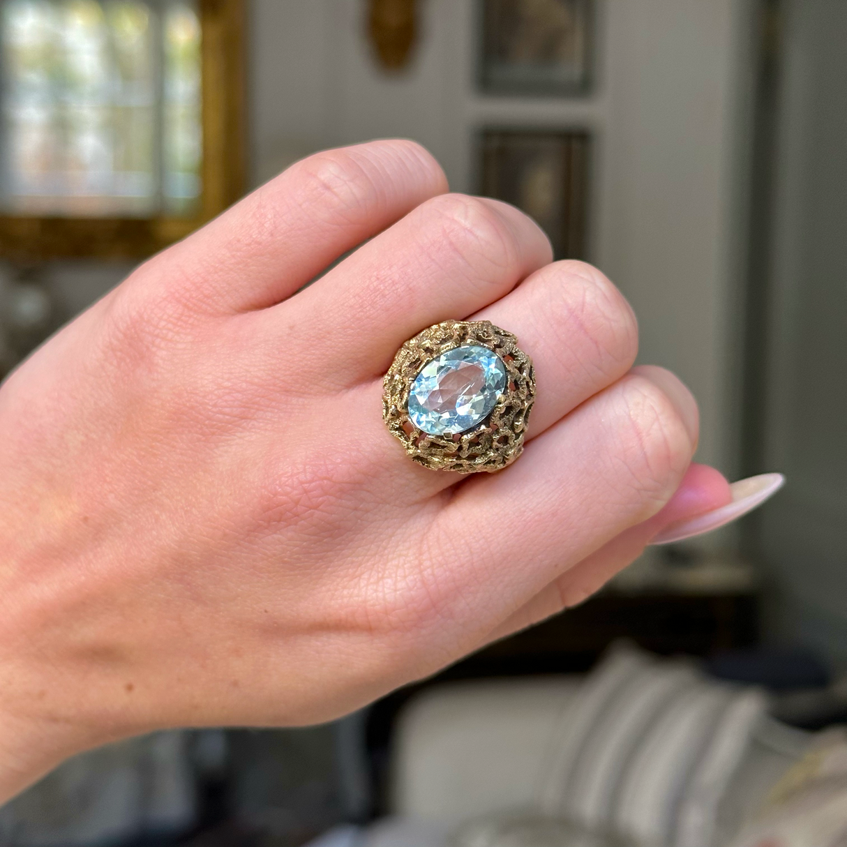 aquamarine ring with naturalistic textured yellow gold band on closed hand.