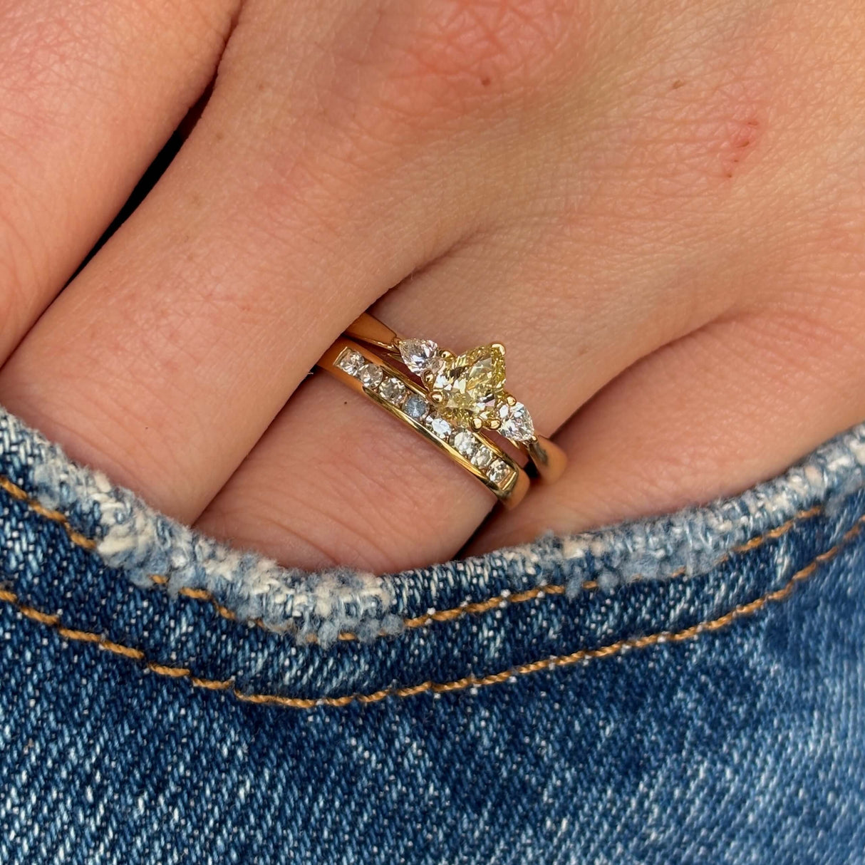 Pear-cut diamond three-stone engagement ring worn with a wedding band to show proportions and fit.