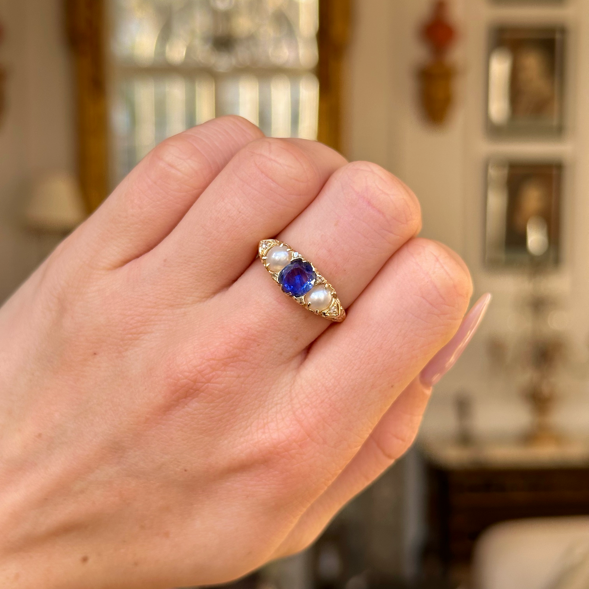 antique sapphire and pearl three stone ring worn on closed hand.