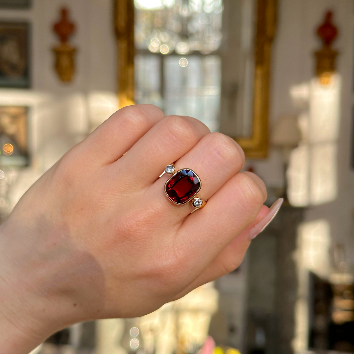 Vintage red zircon and diamond three stone ring worn on closed hand.