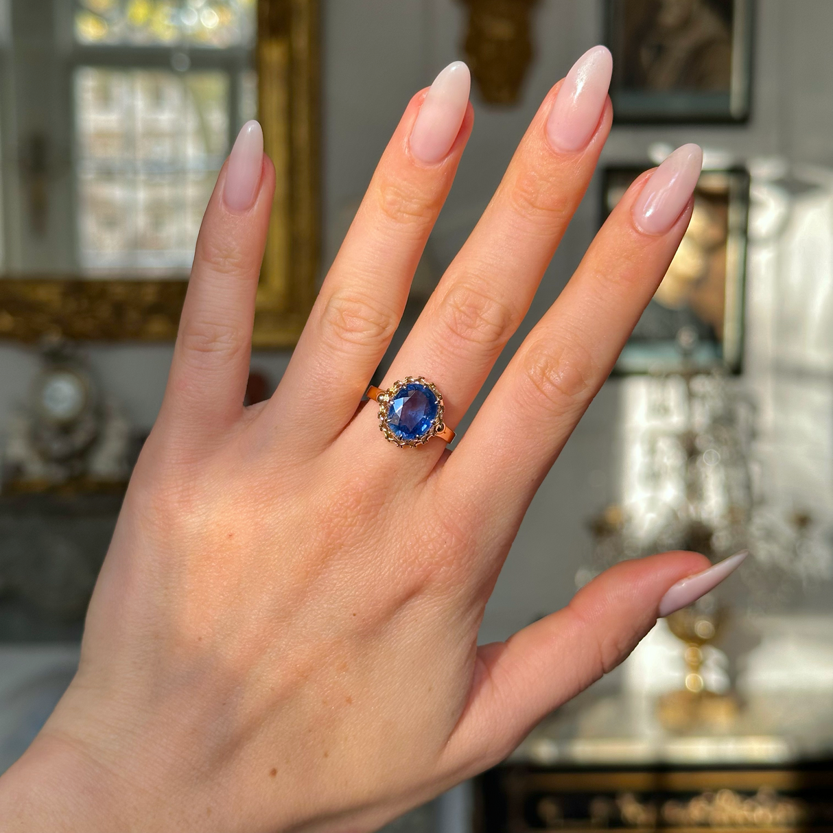 sapphire and yellow gold engagement ring worn on hand.
