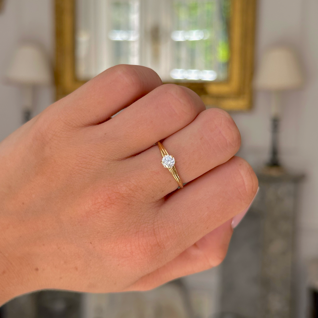 Vintage solitaire diamond engagement ring, worn on closed hand.