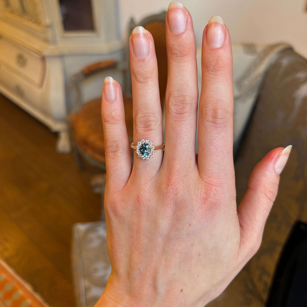 Teal sapphire and diamond cluster engagement ring worn on hand