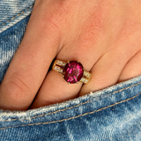Red tourmaline and diamond cocktail ring, worn on hand and placed in pocket of jeans, front view. 