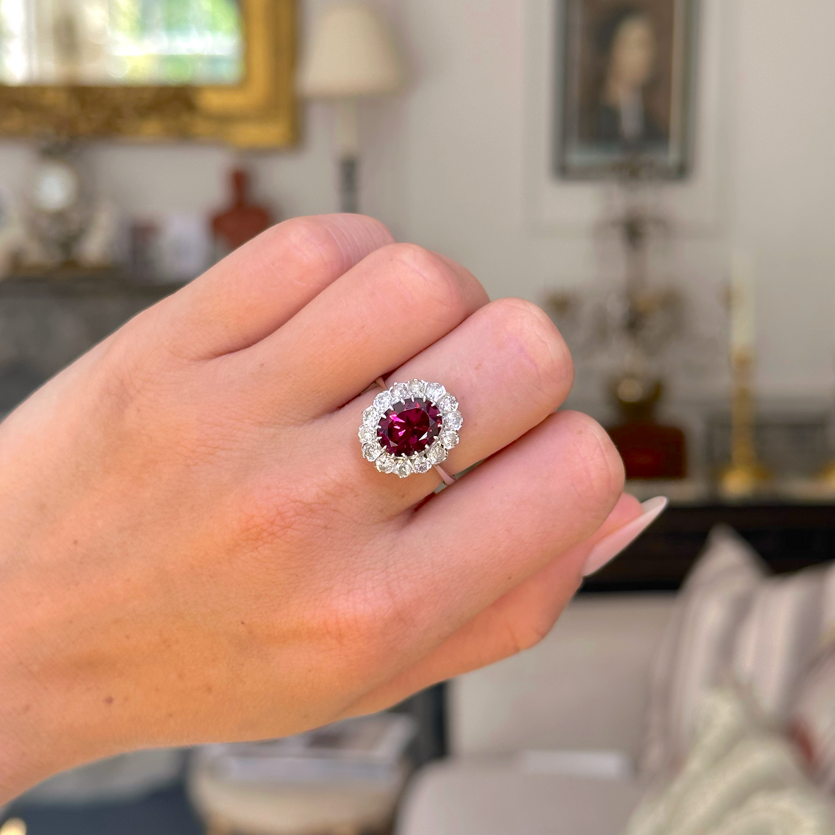 red tourmaline and diamond cluster ring, worn on closed hand, front view.