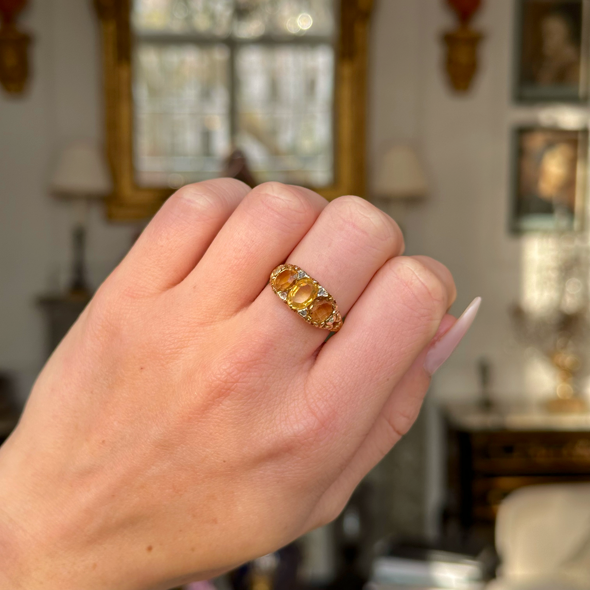 Three stone citrine ring worn on closed hand.
