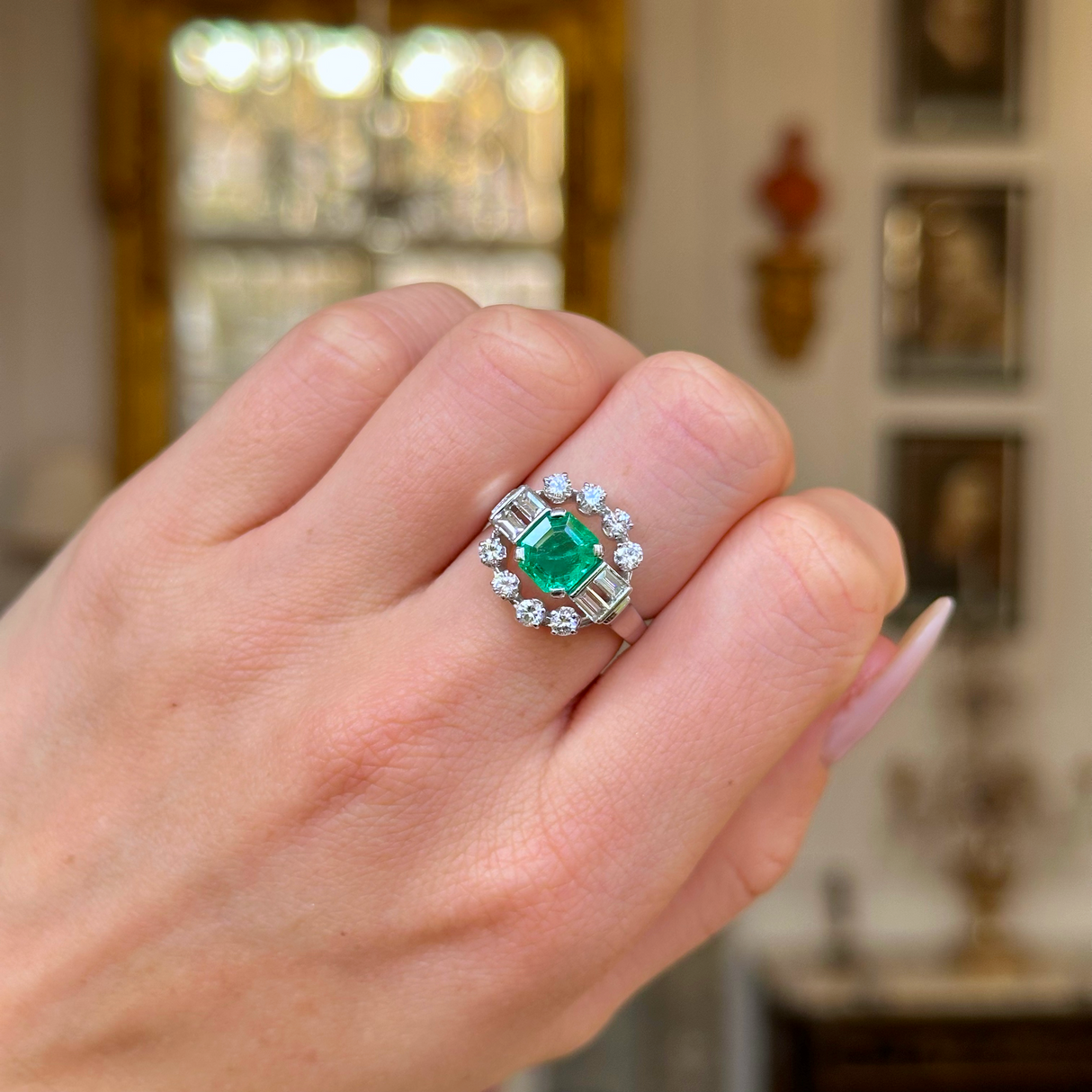 Vintage emerald and diamond ring worn on closed hand.