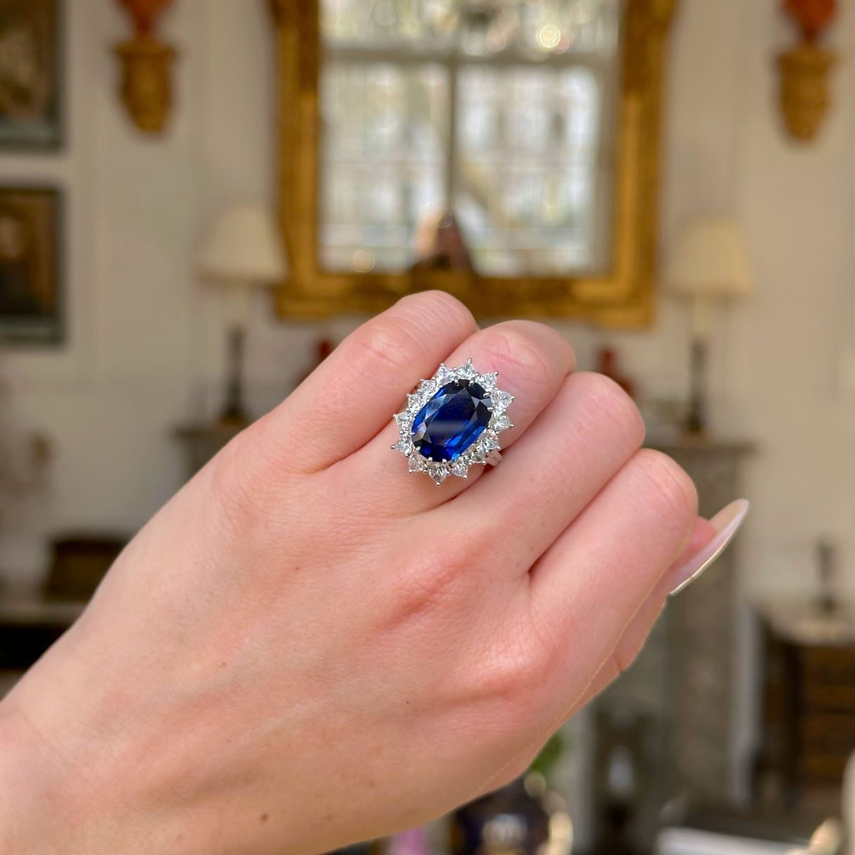 A vintage sapphire and diamond cluster ring worn on closed  hand.