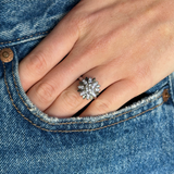 french diamond engagement ring resembling a flower worn on hand inside pocket of jeans, front view. 