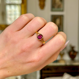 Vintage single-stone ruby and yellow gold ring, worn on closed hand. 